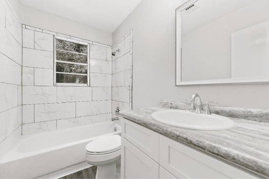 White bathroom remodel with marble Bold kitchen remodel with brass fixtures and blue accents